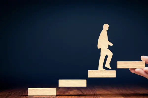 Wooden silhouette of a man walking up a staircase.