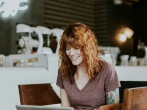 Girl with red hair and arm tattoo working at a coffee shop.
