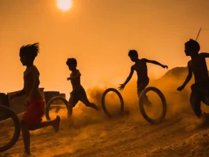 Silhouettes of kids playing with tires in the desert.