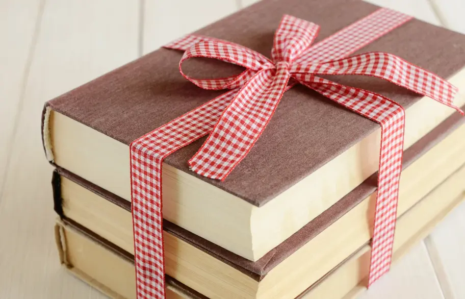 Stack of books tied with a red and white checkered ribbon.