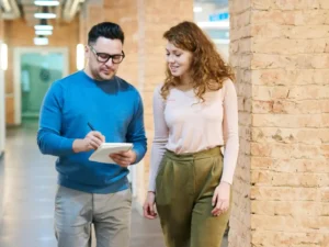 Coworkers standing next to each other while one writes on a notepad.